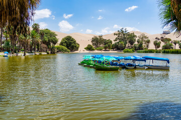 Paddle boats docked on the serene lagoon of Huacachina, a desert oasis near Ica, Peru.