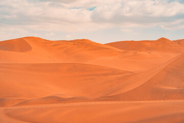 Naklejka premium Golden sand dunes of Ica desert under a clear blue sky in Huacachina, Peru