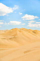 Golden sand dunes of Ica desert under a clear blue sky in Huacachina, Peru
