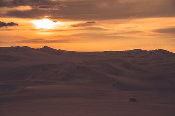 Ica desert landscape at sunset with smooth golden sand dunes near Huacachina, Peru.