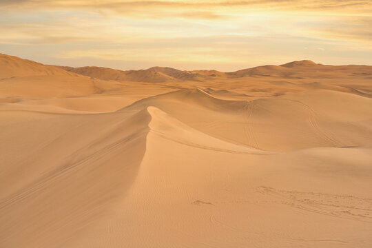Ica desert landscape at sunset with smooth golden sand dunes near Huacachina, Peru.