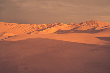 Ica desert landscape at sunset with smooth golden sand dunes near Huacachina, Peru.