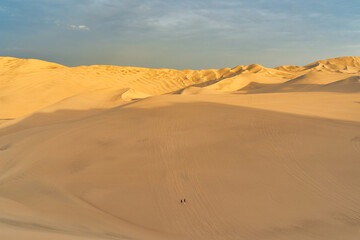Ica desert landscape at sunset with smooth golden sand dunes near Huacachina, Peru.