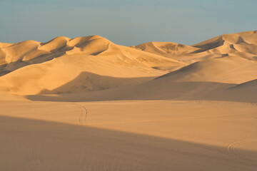 Ica desert landscape at sunset with smooth golden sand dunes near Huacachina, Peru.