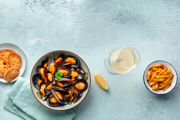 Mussels with French fries and white wine, moules frites, overhead flat lay shot on a slate background with a place for text