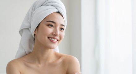 Smiling Asian woman in towel wrap looking sideways in soft light