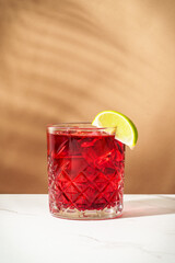 New Yorker red cocktail with whiskey, grenadine, bitter, lime and ice in glass.