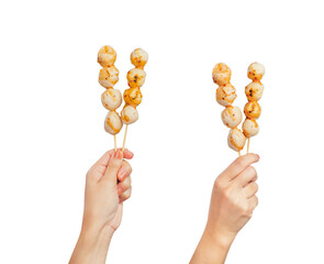 Hand holding meatball stick with spicy sauce isolated on white background.
