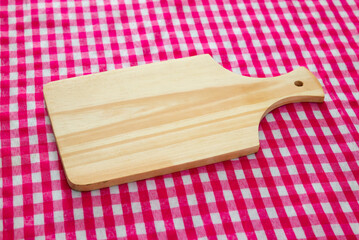 Wooden cutting board with red checkered tablecloth background