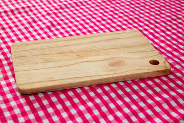 Wooden cutting board with red checkered tablecloth background
