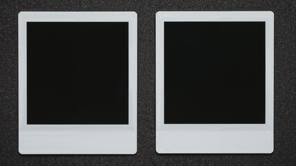 Two blank instant photos lying on black background