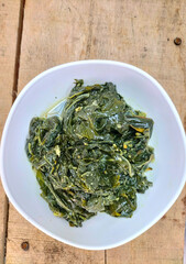 Selective focus. Daun singkong or Cassava leaf curry is a traditional Indonesian dish, made from boiled cassava leaves, seasoning with coconut milk and spicy curry spices. 