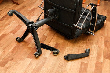 An office chair on the floor with broken legs: a symbol poor workmanship and the need for repairs.