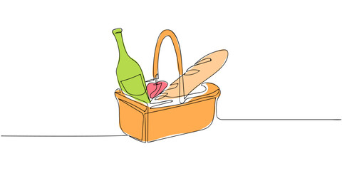 Basket containing wine, bread, cheese, and fruit prepared for a picnic in a sunny outdoor setting