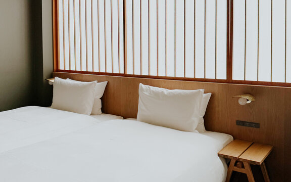 Minimalist Japanese hotel room with twin beds and soft white bedding, shoji screen. Modern ryokan interior 