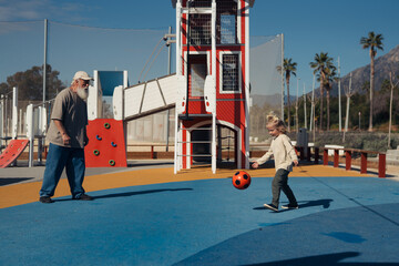 A joyful moment shared between a grandfather and his grandchild as they play catch with a soccer...