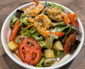 Mixed vegetable salad with lettuce, tomatoes, cucumbers, and carrots, topped with sesame or Caesar dressing. A fresh and healthy choice.