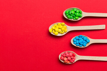 delicious colorful sweet candies on spoon on colored background . Confectionery decor top view with copy space