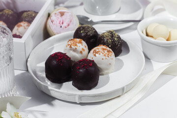 Handmade round chocolate candies on a white plate. Chocolates without sugar. Healthy dessert