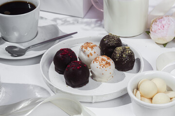 Handmade round chocolate candies on a white plate. Chocolates without sugar. Healthy dessert