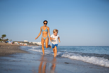 Fototapeta premium Mother and Son Running Together on a Sunny Beach