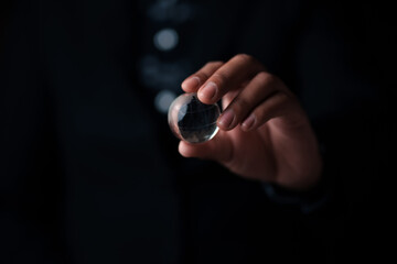 Mystical hand holding crystal sphere dark background conceptual photography studio setting close-up perspective