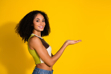 Smiling woman showcasing an open hand gesture in front of bright yellow background