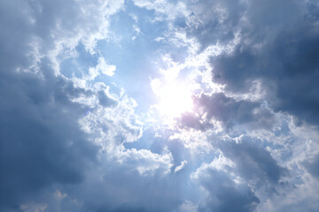 a plane flying through a cloudy sky with the sun shining through the clouds