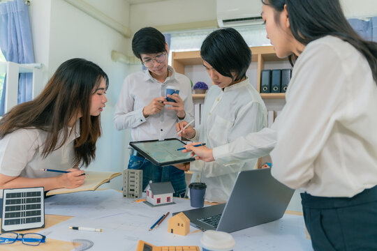 Team of young Asian architects planning new project using blueprints and construction tools on meeting table in office, teamwork and industry concept. - Powered by Adobe