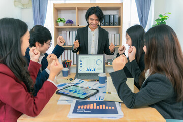 Fototapeta premium Group of young Asian businesswomen presenting financial sales report to colleagues in a diverse team, pointing at tablet screen on electronic board.