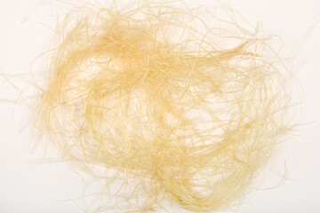Overhead shot displays a small pile of light brown and yellow corn silk threads on a plain white background