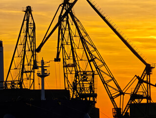 Industrial Port Cranes Silhouetted Against Sunset Sky. Maritime Logistics and Global Trade Concept