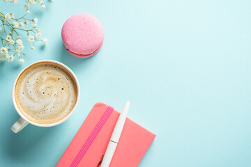 Cup of coffee, macaroon and flower on blue background.