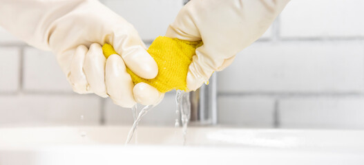 Close-up shot of woman in rubber gloves cleans sink and faucet with a rag and spray in the...