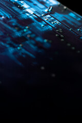 Illuminated blue electronic circuit board with electrical components and connections, isolated on black. Selective focus. Copy space