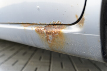 Close-up of rusty car sill with corrosion damage.