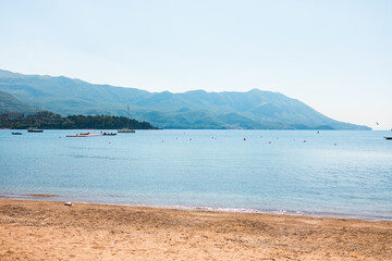 Tranquil beach with calm sea and mountain background. Coastal serenity, nature landscape, and summer relaxation destination.