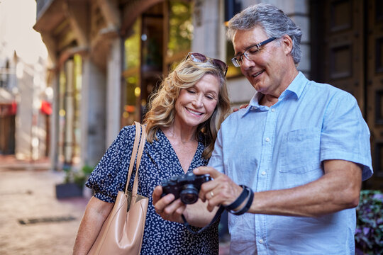 Senior couple reviewing photos during vacation - Powered by Adobe