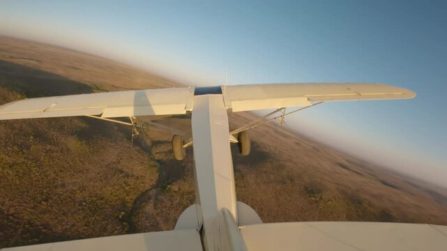 Extreme wide tail view of a bushcraft plane flying over a river hills outlined by sunrise in savanna kenya
