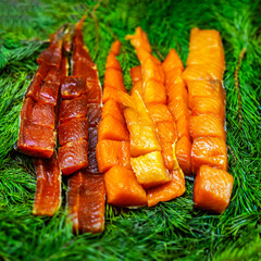 Slices of smoked fish arranged on fir branches for rustic food presentation. Concept of smoked fish, traditional cuisine, freshness and gourmet delicacy. Healthy eating and fish market concept