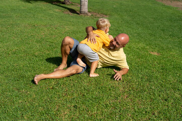 cheerful father plays with his son in the park. father and son on the green lawn having fun