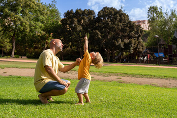 Cheerful father and son looking at each other while laughing at park on sunny day. father and son hugging in the park. communication between father and little son