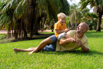 cheerful father plays with his son in the park. father and son on the green lawn having fun
