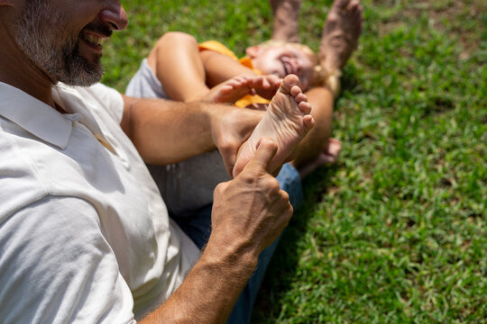 family and love concept - young father tickling his little son in park. close-up of a child's heel and the father's hand who tickles him. cheerful baby laughs from being tickled
