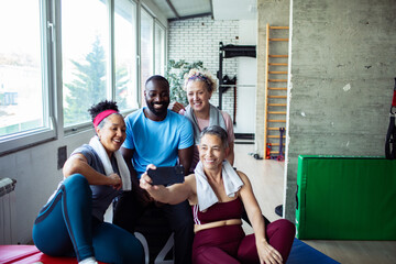 Diverse group of happy seniors and fitness trainer taking a post-workout selfie at the gym