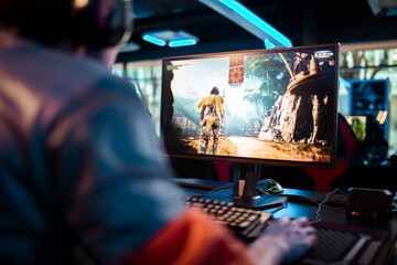 Rear view of a man gaming on a PC in a modern esports arena