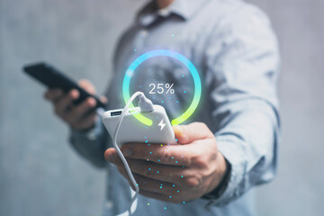 Close-up of hands holding a Smartphone connected to a portable Power Bank, with a glowing digital battery indicator showing the percentage of charge.