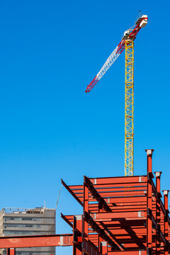 Green crane and red steel beams, elevated construction view with vibrant structural elements and clear separation from sky background