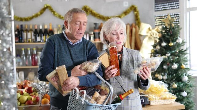 Happy elderly couple choosing products for Christmas table in supermarket - nougat, marzipan, panellets and other sweets. High quality 4k footage