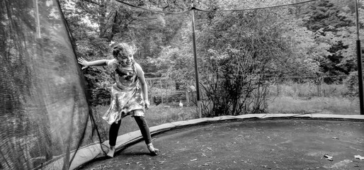 Black and White photo of a girl inside a trampoline, while putting her hand on the net